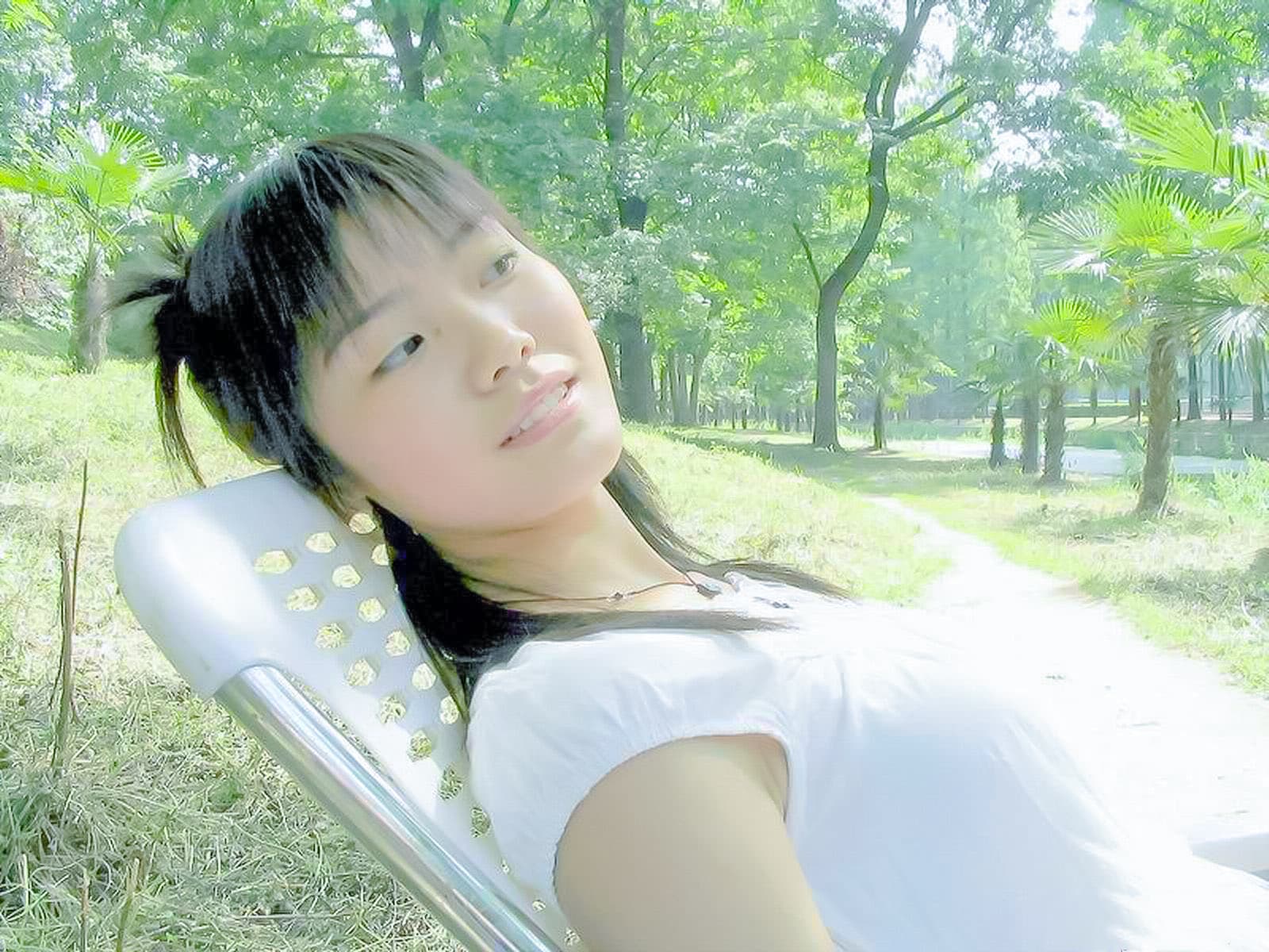Woman seated on a park bench wearing short sheer nylons, one shoe removed to reveal a bare, well-arched foot against sunlight